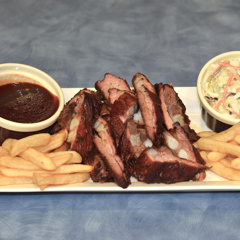 Kenny's Ribs and Chicken's BBQ ribs, french fries, coleslaw, and a side of BBQ sauce.